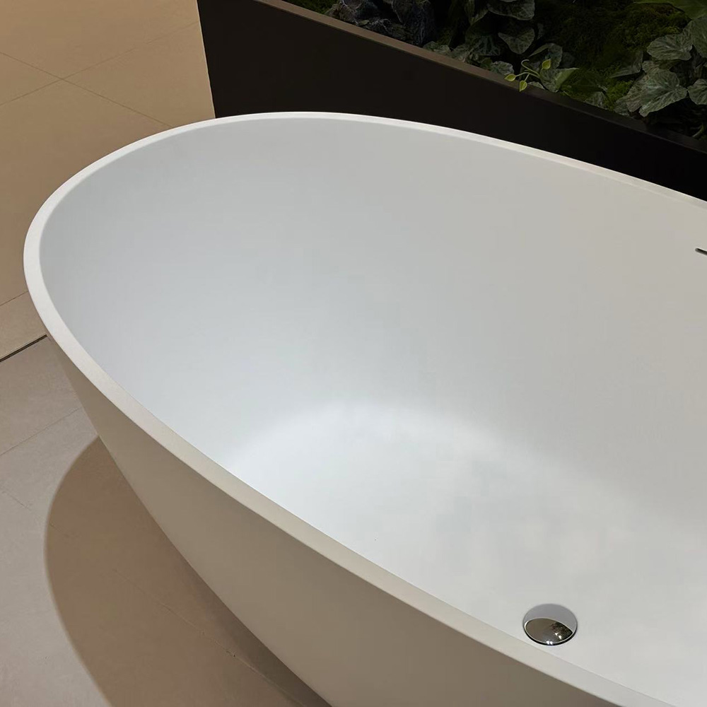 White artificial stone bathtub with a matte interior and chrome drain